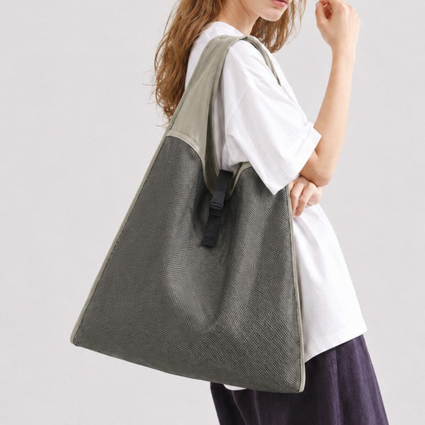 Oversized triangular mesh tote bag with matte olive-khaki fabric straps and trim, dark open-weave mesh body, matte black