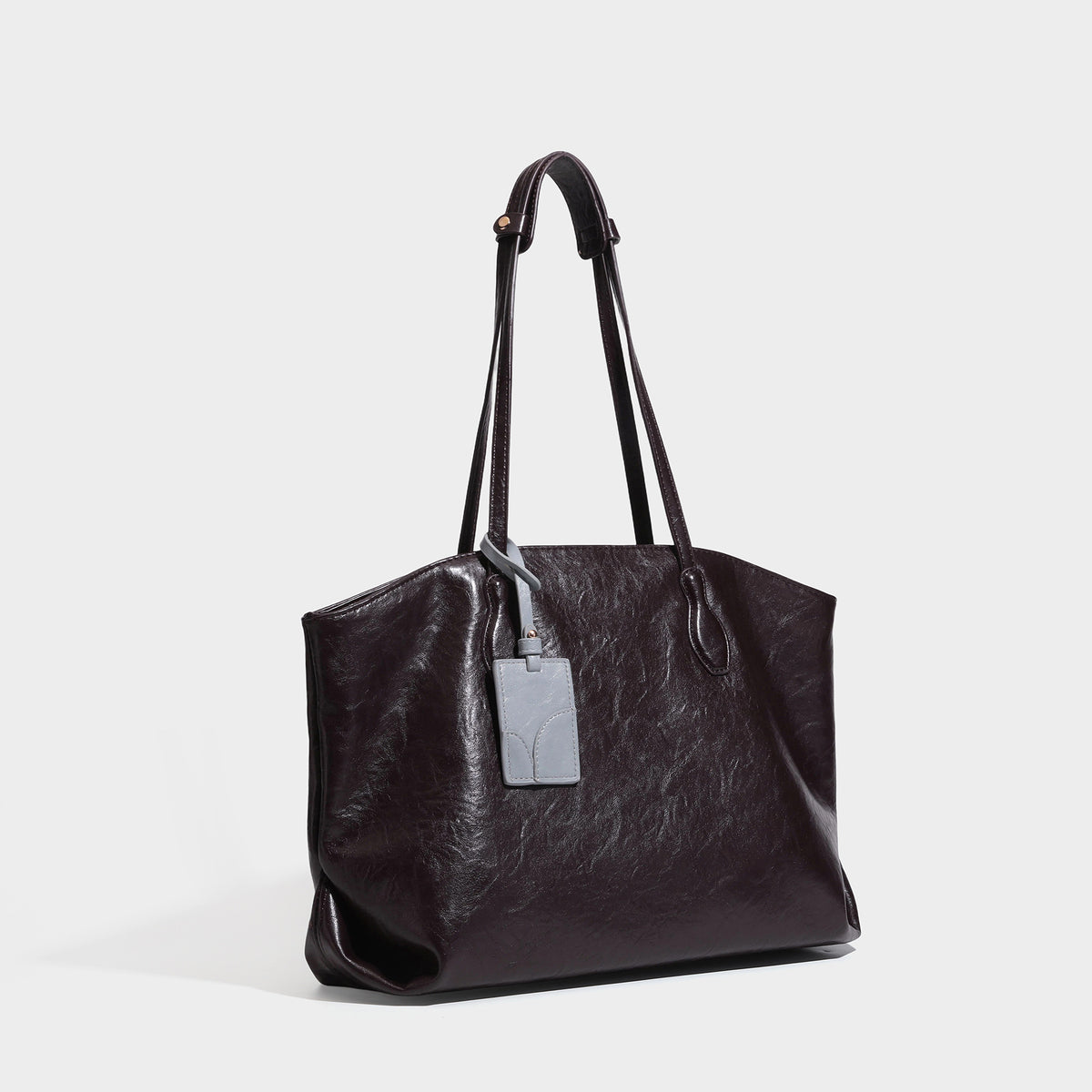 Oversized-Shopper mit lässig-weicher Form in dunkler Burgunderfarbe, glänzender geknautschter Lederoptik, zwei langen Schulterriemen und kontrastierendem