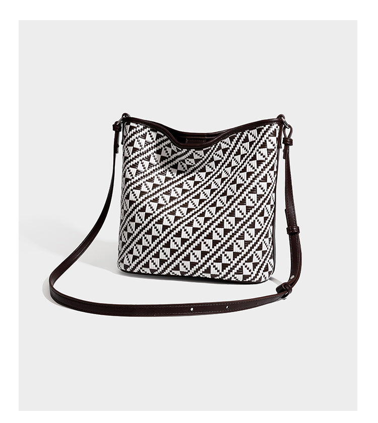 Geflochtene Schultertasche mit geometrischem Ethno-Muster, Besatz in dunkelbrauner Lederoptik, langem verstellbarem Träger und kleinem hängendem Reißverschluss