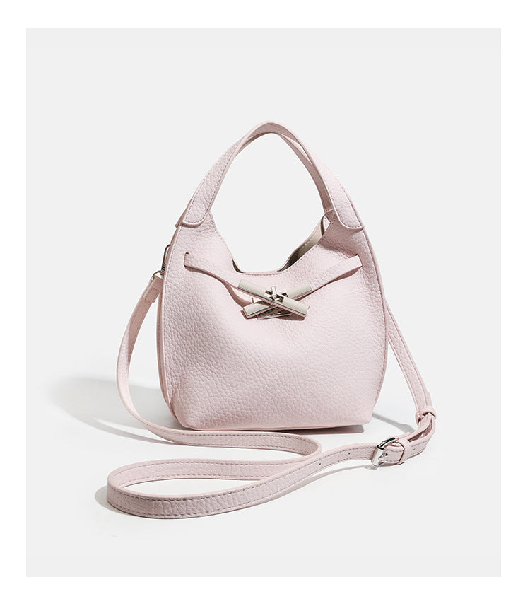 Compact pebbled leather-look shoulder bag with crossed silver-toned metal front closure, short top handle, and long, detail