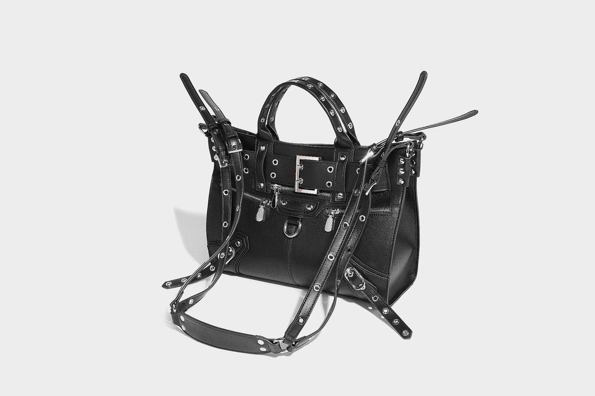Black structured rectangular satchel bag with silver-tone rivets, large front buckle strap, zip pockets, dual top handles