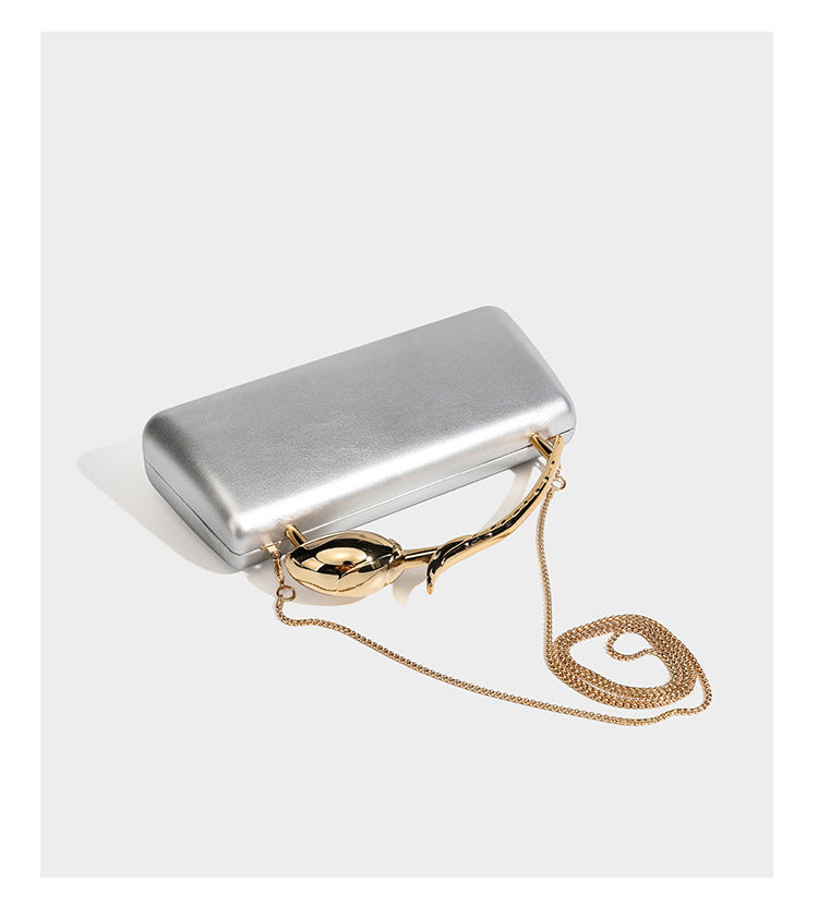 Formstabile, rechteckige Clutch mit Henkel in Rosenknospenform in Goldoptik und abnehmbarem Kettenriemen in Metallic-Optik, Detail