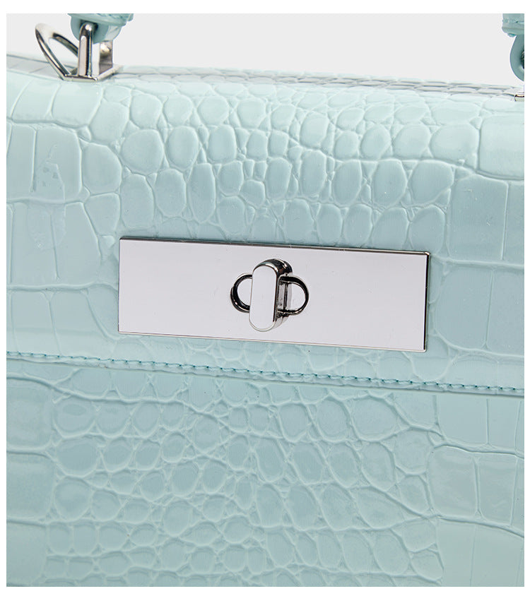 Small structured rectangular satchel with glossy crocodile-embossed finish, arched top handle, front flap, and silver-tone