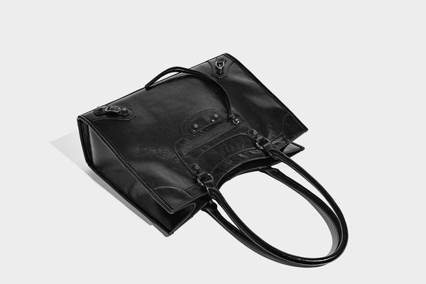 Large structured leather-look tote bag with front zip pocket, moto hardware accents, and long double shoulder straps, detail