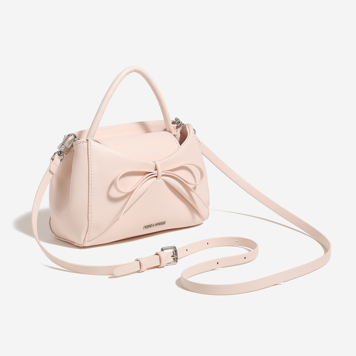 Small structured trapezoid handbag with a three-dimensional front bow, short top handle, and detachable shoulder strap