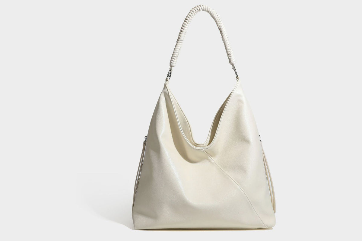 Large slouchy hobo shoulder bag with braided top handle, smooth glossy leather-look finish, and silver-tone ring hardware