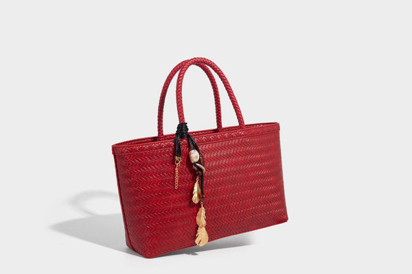 Structured woven-texture tote bag with brown braided top handles, decorative tassel charm, and detachable shoulder strap