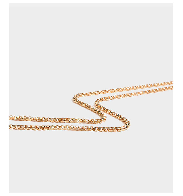 Structured rectangular metallic woven clutch bag with sculptural gold-tone leaf top handle and detachable chain strap, detail