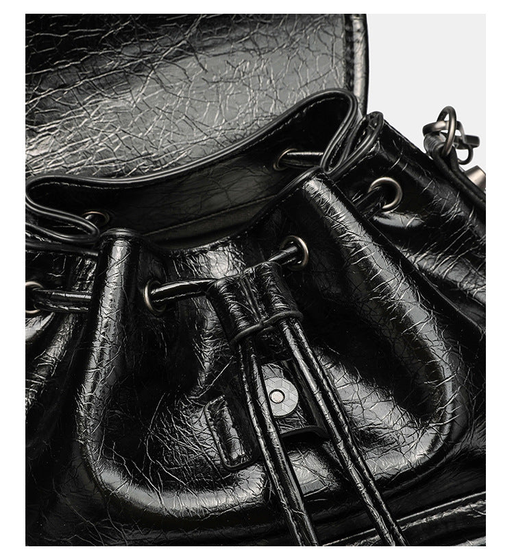 Small structured glossy leather-look convertible backpack handbag in black with flap closure, front zip pockets, metal stud