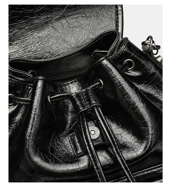 Small structured glossy leather-look convertible backpack handbag in black with flap closure, front zip pockets, metal stud