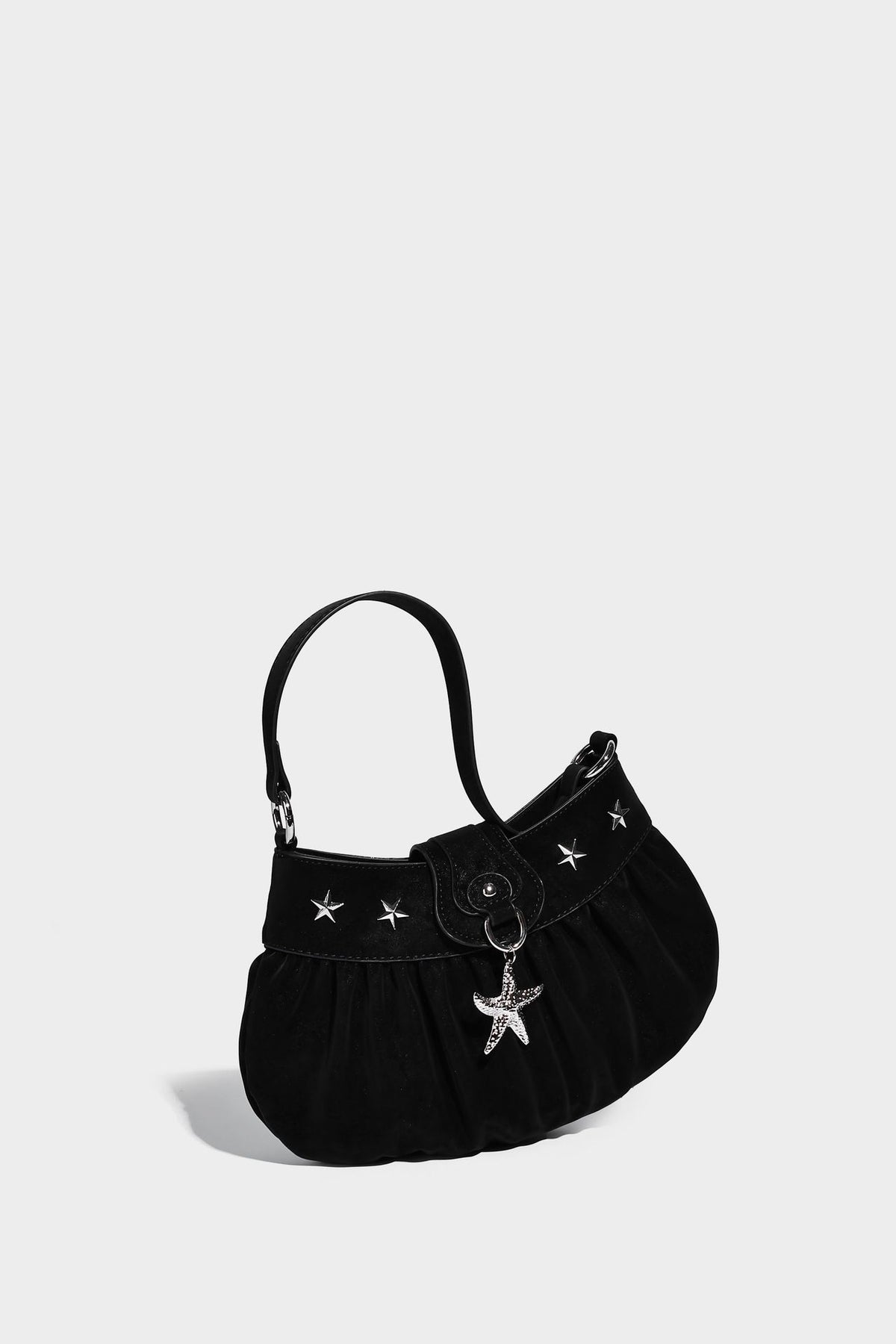 Ruched shoulder bag with curved flap, silver star studs, dangling starfish charm, and adjustable crossbody strap, detail view
