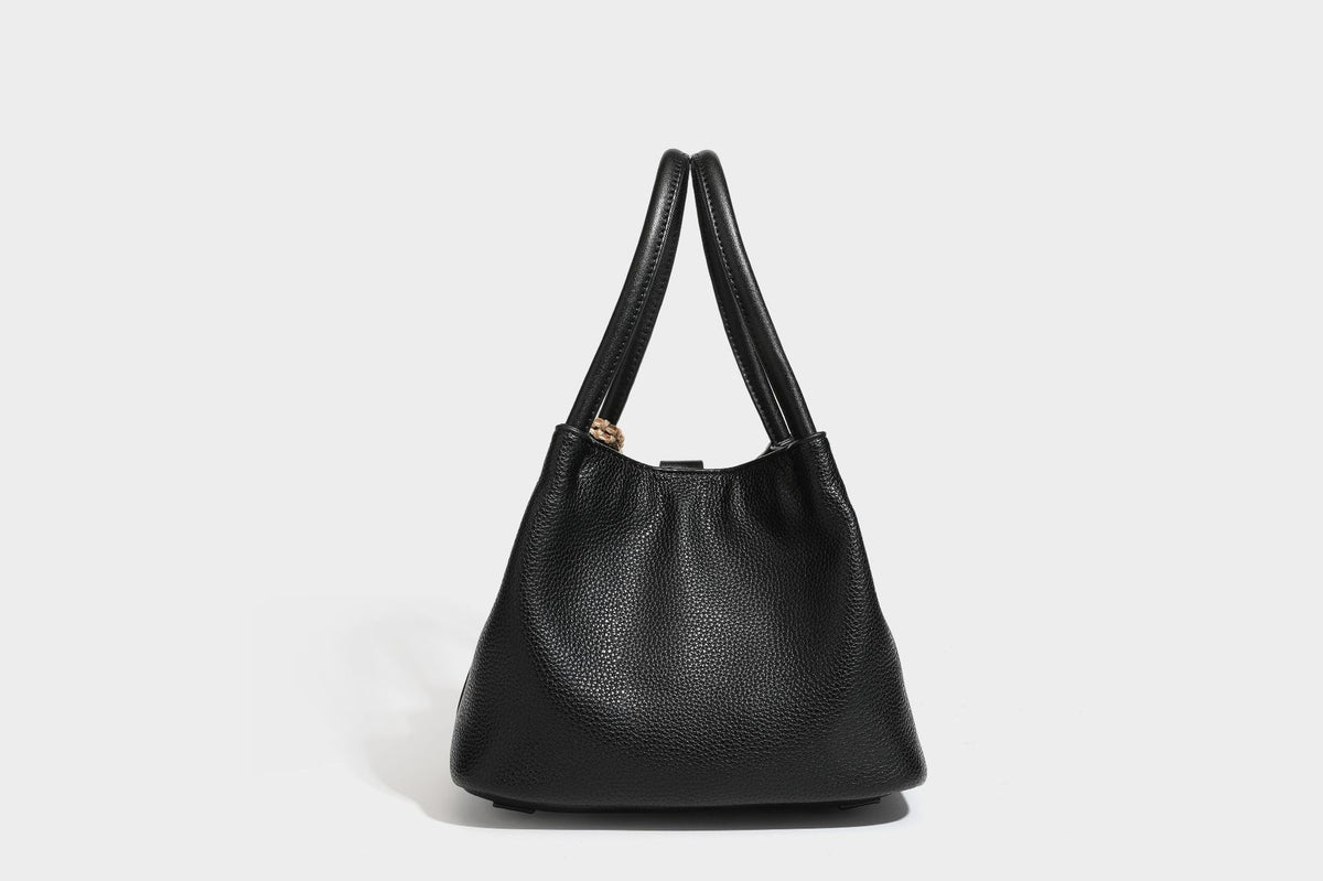 Pebbled leather-look bucket tote bag with rolled double handles, drawstring closure, braided cord charm, and detachable