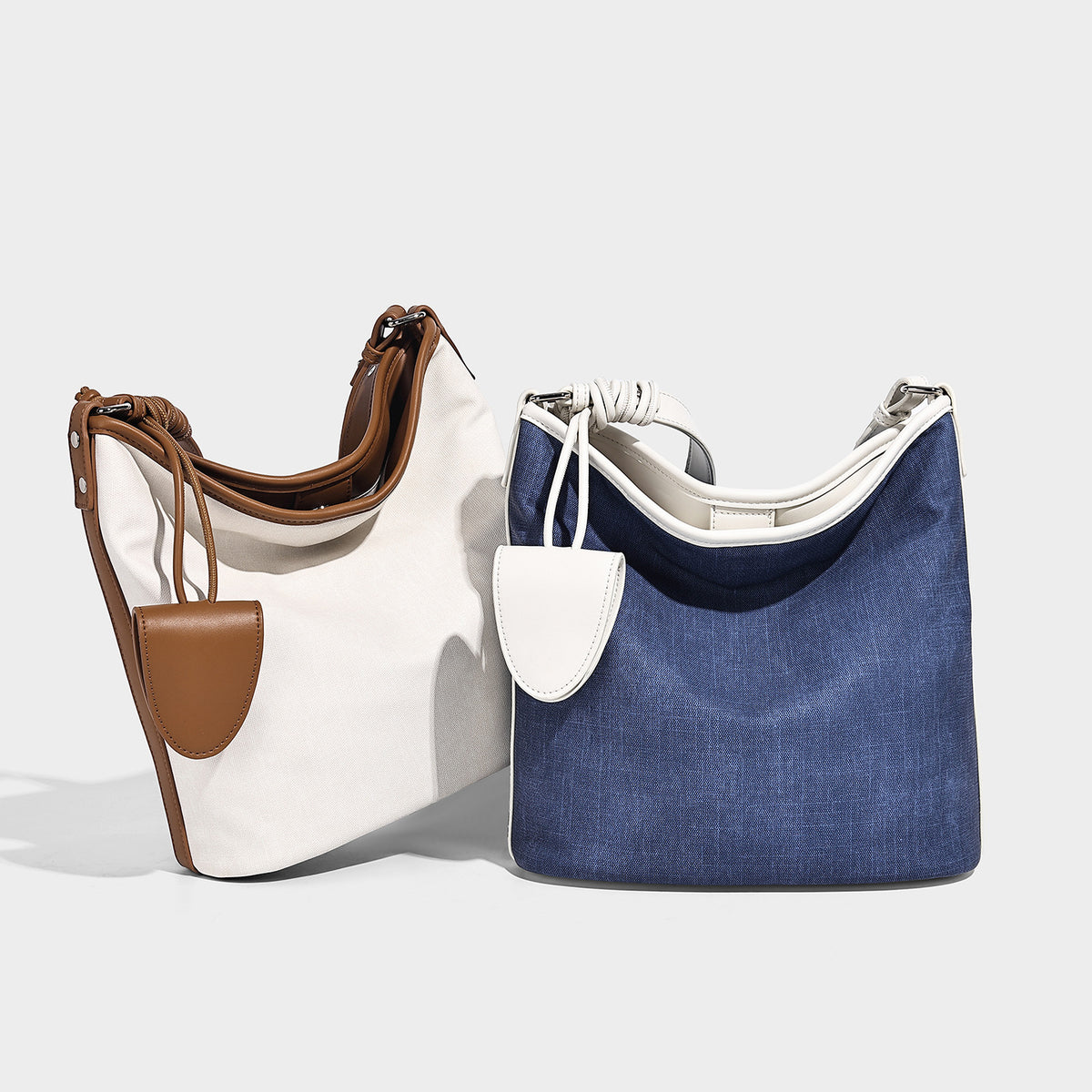 Large denim-look canvas bucket shoulder bag with white leather-look trim, knotted strap, and removable front mini pouch