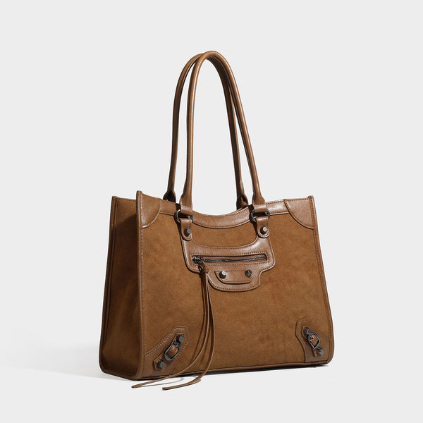 Large structured tote bag with matte suede-like body, smooth leather-look trim, front zip pocket, stud hardware, and