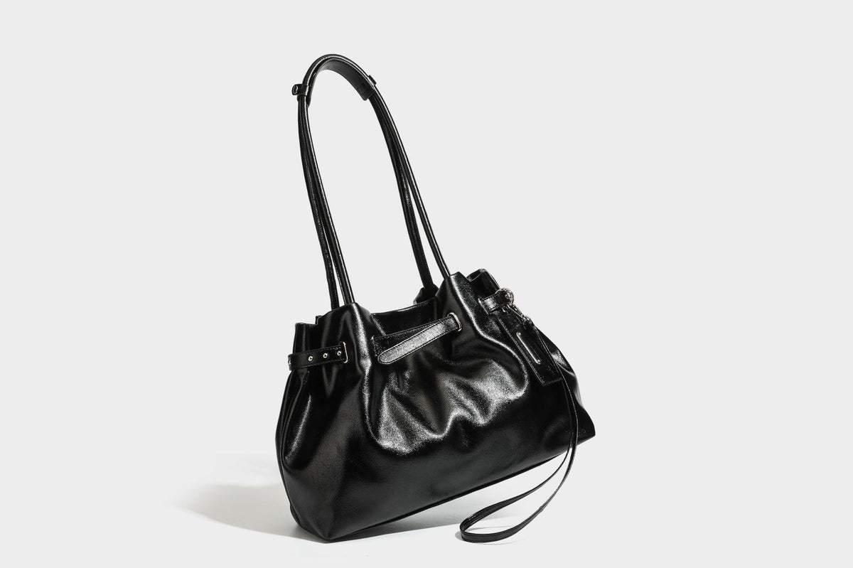 Glänzende schwarze, weich fallende Schultertasche mit gerafftem Abschluss, zwei langen Trageriemen, silberfarbenen Beschlägen und abnehmbarem Umhängeriemen