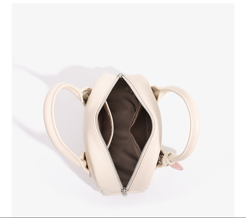 Mini-Handtasche in Kuppelform mit glatter Oberfläche in Lederoptik, zwei Henkeln, Reißverschluss oben, silberfarbenen Metalldetails und herabhängendem
