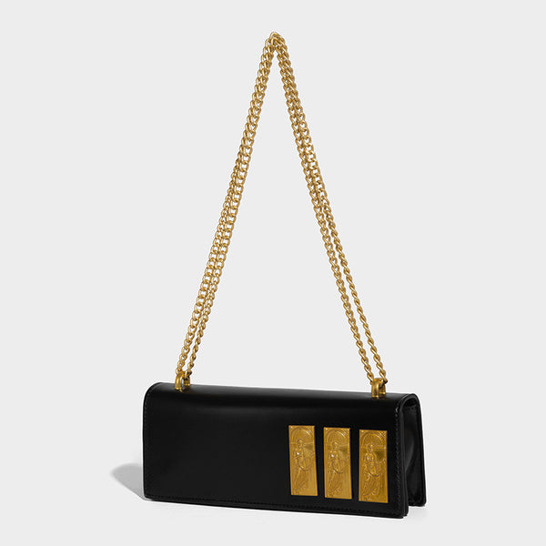 Structured rectangular crossbody bag with glossy finish, three vertical gold-tone embossed plaques, and gold chain strap