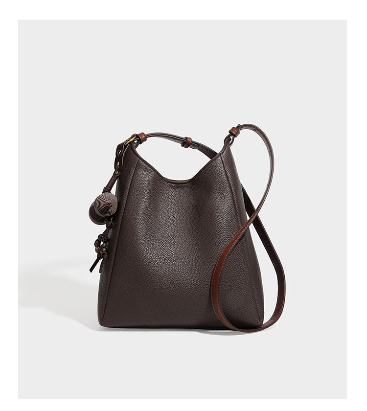Hobo-Schultertasche in dunklem Espresso mit genarbter Oberfläche, warmen cognacfarbenen Details, verstellbarem schmalem Riemen, goldfarbenen Ringbeschlägen und geknotetem