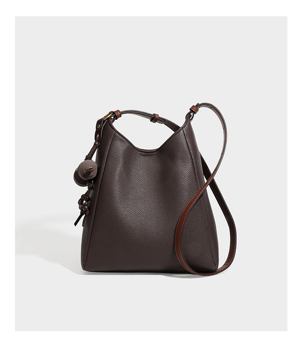 Hobo-Schultertasche in dunklem Espresso mit genarbter Oberfläche, warmen cognacfarbenen Details, verstellbarem schmalem Riemen, goldfarbenen Ringbeschlägen und geknotetem