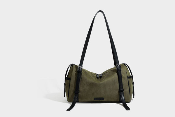Olivgrüne Canvas-Schultertasche in Zylinderform mit schwarzen Trägern in Lederoptik, Reißverschluss oben und silberfarbenen Metallbeschlägen, Detailansicht