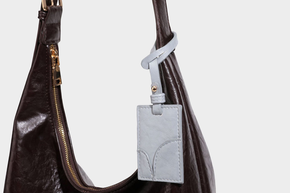 Große dunkelbraune, glänzende, geknautschte Hobo-Schultertasche mit Reißverschluss, goldfarbenen Metalldetails, verstellbarem Trageriemen und Hellblau