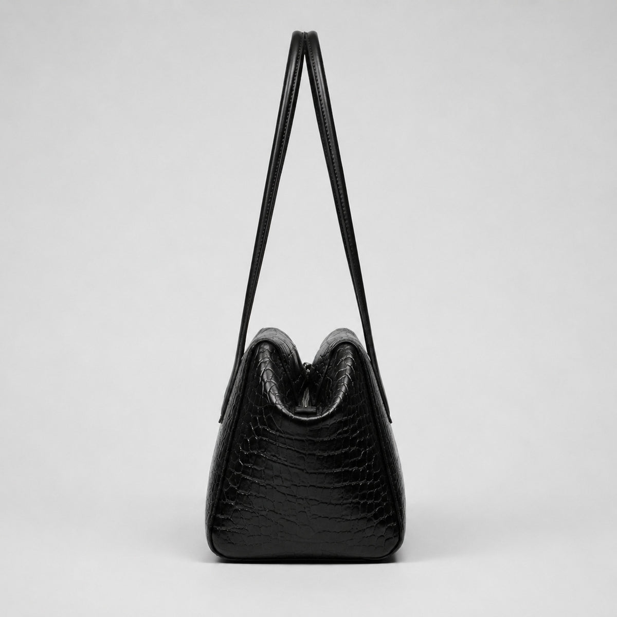 Schwarze glänzende Schultertasche in Trapezform mit Krokoprägung, zwei abgerundeten Riemen und Reißverschluss, Detailansicht 14