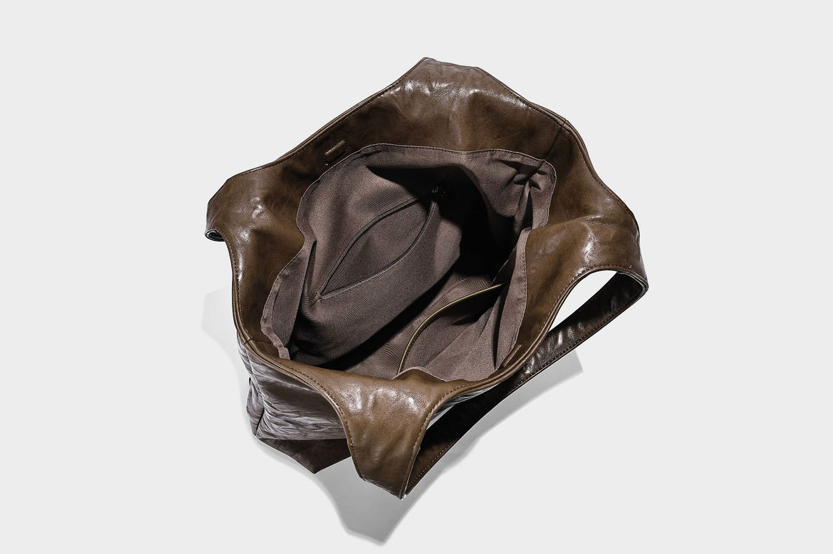 Large open-top tote bag with crinkled leather-look finish, long double shoulder straps, and embossed circular detail on