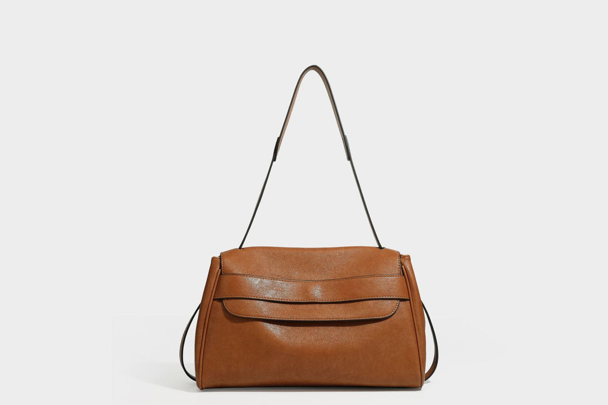 Strukturierte rechteckige dunkelbraune Schultertasche in Lederoptik mit Klappe, mehrlagigem Detail auf der Vorderseite und langem verstellbarem Riemen, Detailansicht