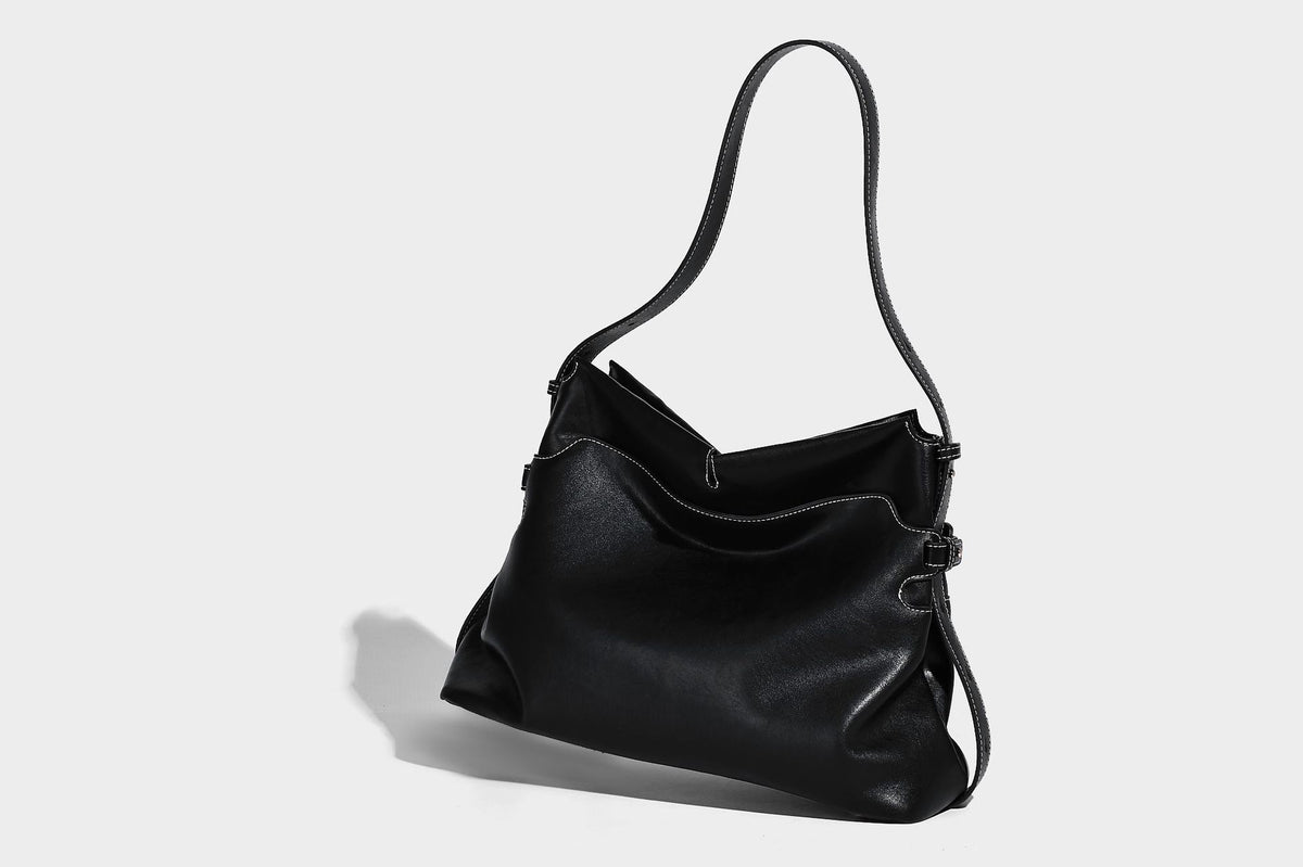 Large slouchy leather-look hobo tote bag with open top, adjustable shoulder strap, and colorful tassel bead charm, detail