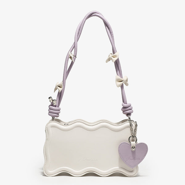 Small structured scalloped-edge shoulder bag with bow-tied pink cord strap and silver heart charm pendant, front view