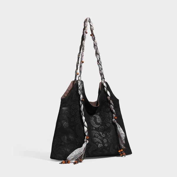 Slouchy paisley-embossed suede-look shoulder tote bag with braided patterned fabric straps and wood bead accents, detail view