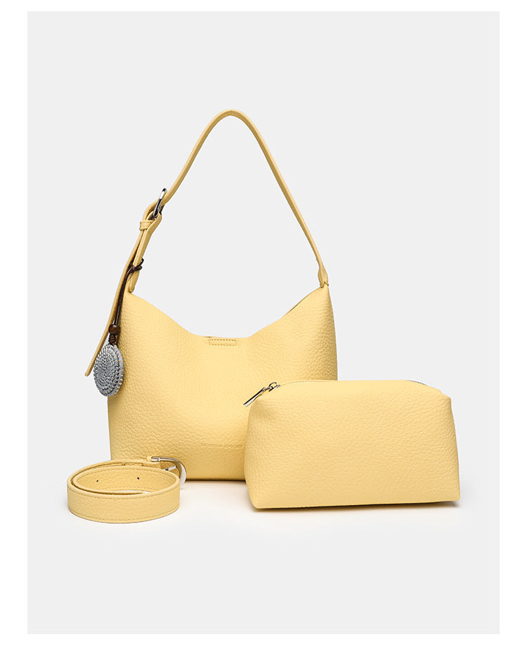 Slouchy hobo shoulder bag in pale yellow pebbled texture with woven charm, adjustable strap, matching zip pouch, and, detail