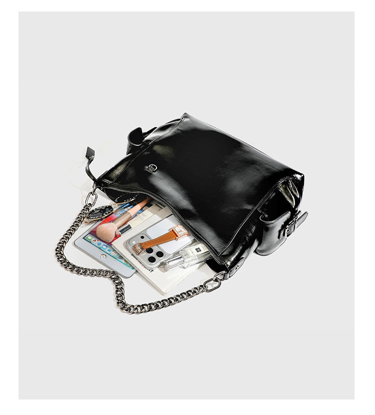 Slouchy hobo shoulder bag with glossy leather-look finish, silver-tone chain drape across front, side buckle pockets, and