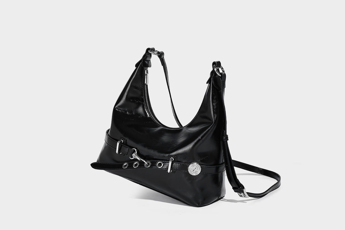 Glossy black slouchy hobo shoulder bag with silver-tone hardware, belt-style grommet strap at base, and long adjustable