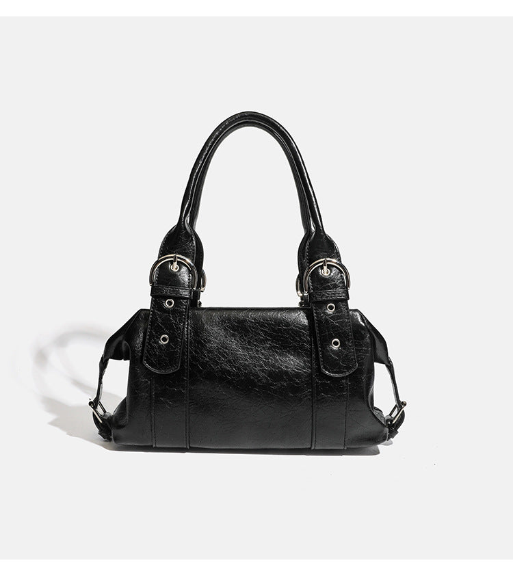 Compact black glossy leather-look satchel bag with silver-tone rivets, buckle hardware, and dual padded top handles, detail