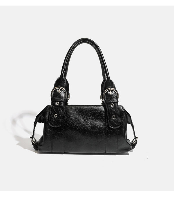 Compact black glossy leather-look satchel bag with silver-tone rivets, buckle hardware, and dual padded top handles, detail
