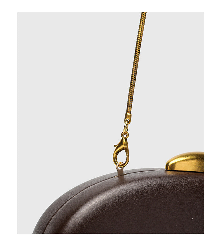 Oval hard-shell crossbody clutch bag with smooth matte leather-look finish and gold-tone snake chain strap, detail view 15