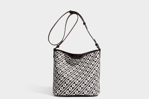 Geflochtene Schultertasche mit geometrischem Ethno-Muster, Besatz in dunkelbrauner Lederoptik, langem verstellbarem Träger und kleinem hängendem Reißverschluss