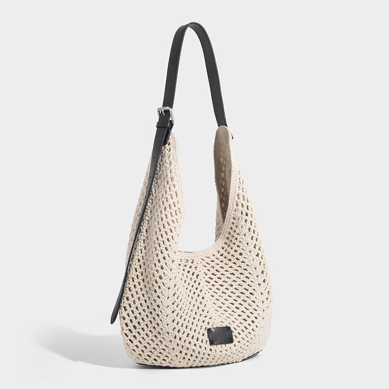 Cream openwork crochet hobo bag with black leather-look strap and trim patch accent, slouchy teardrop silhouette, detail view