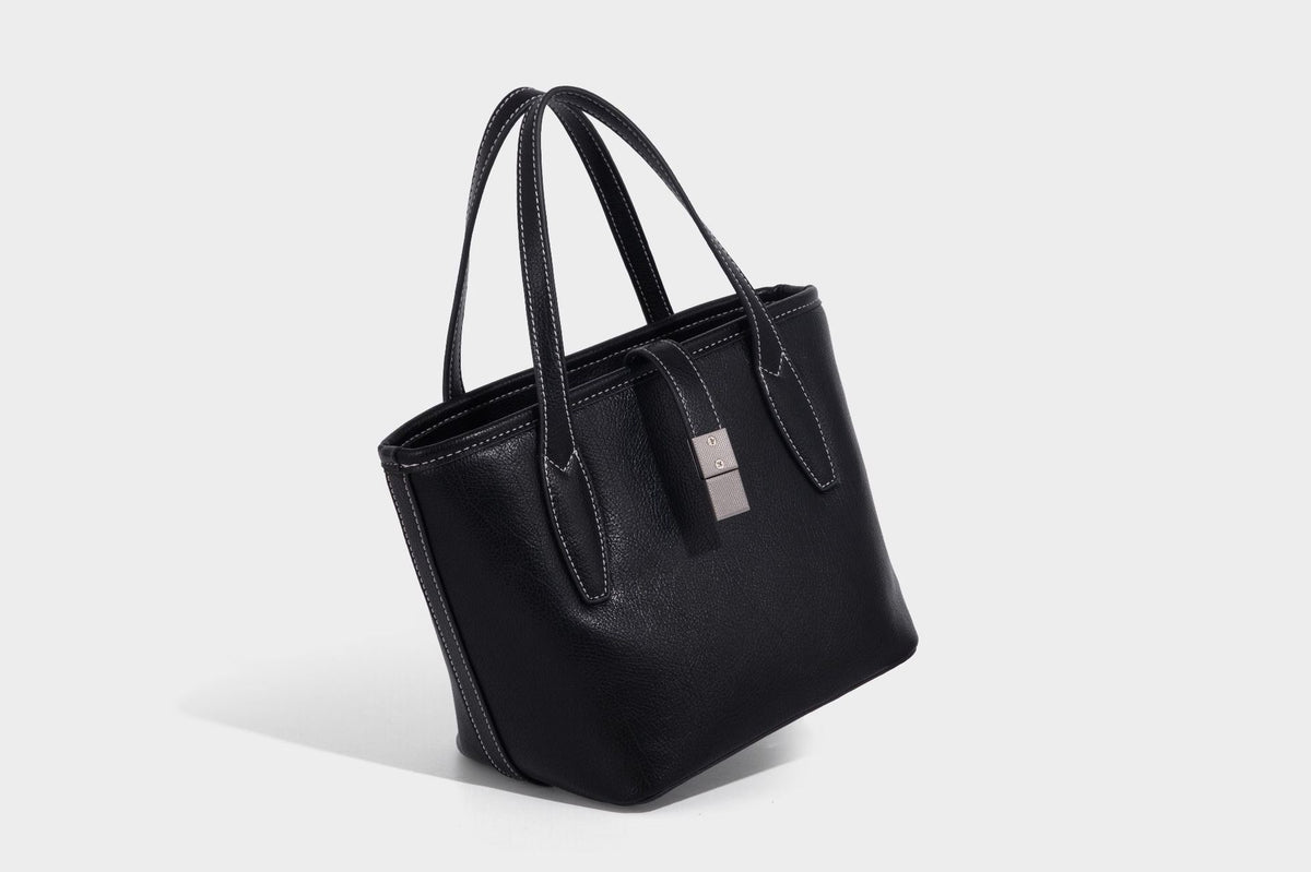 Compact structured bucket tote bag with pebbled textured finish, dual top handles, silver-tone lock hardware, and detachable