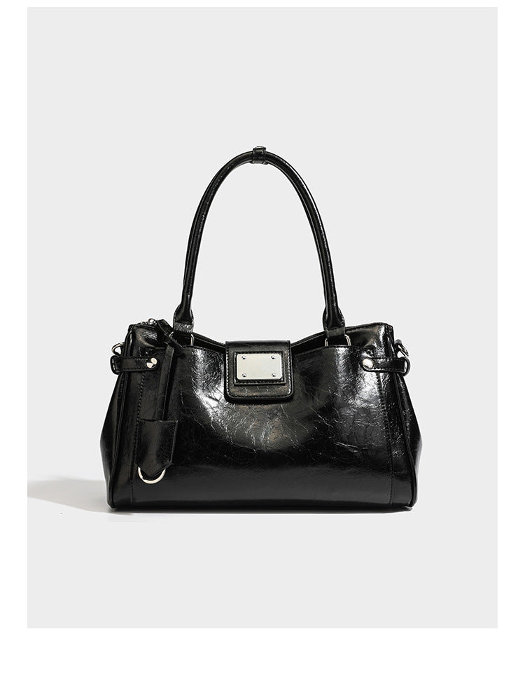 Structured glossy crinkled leather-look satchel with double top handles, front metal-plaque tab, silver-tone hardware, and