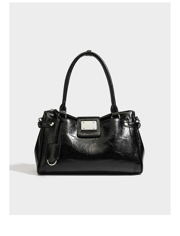 Structured glossy crinkled leather-look satchel with double top handles, front metal-plaque tab, silver-tone hardware, and
