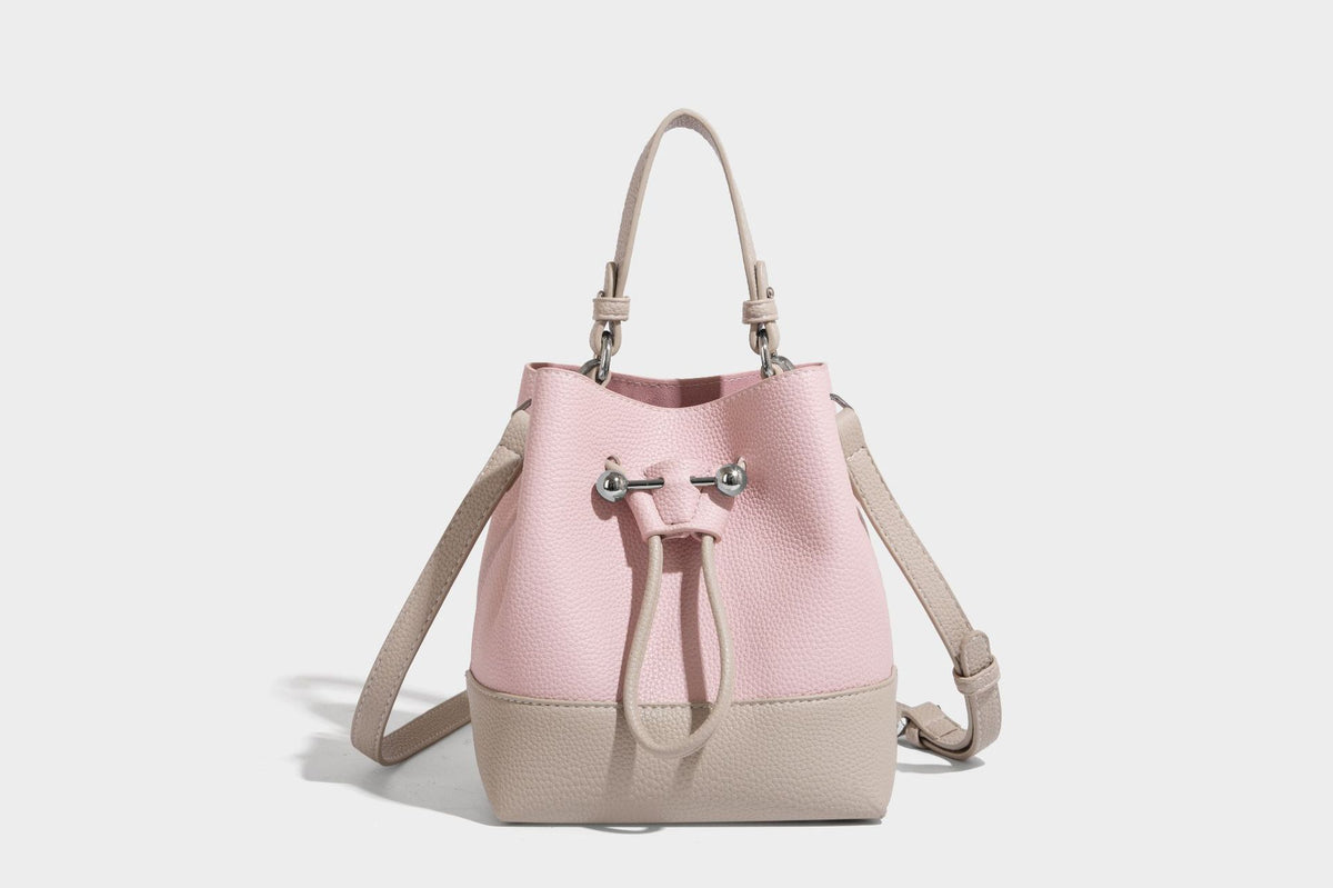 Small two-tone pebbled drawstring bucket bag with tan contrast base, metal toggle hardware, short top handle, and detachable