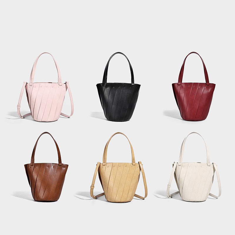 Structured bucket tote bag with vertical panel exterior, dual top handles, and detachable shoulder strap in tan leather-look