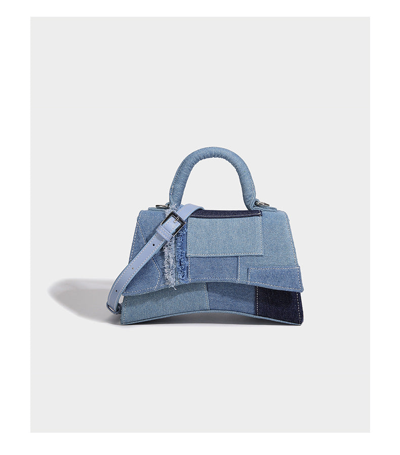 Structured patchwork denim trapezoid satchel bag with frayed panel trim, rounded top handle, and silver-tone hardware, detail