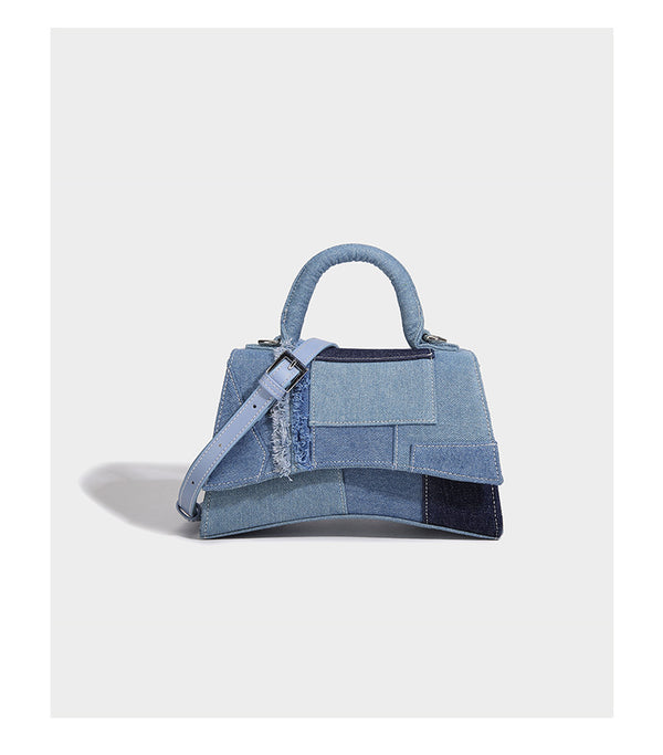 Structured patchwork denim trapezoid satchel bag with frayed panel trim, rounded top handle, and silver-tone hardware, detail