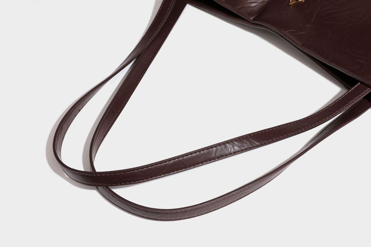 Strukturierte rechteckige Tote-Schultertasche aus glänzender, geknitterter Lederoptik mit langen Doppelträgern und Emblem in Goldoptik