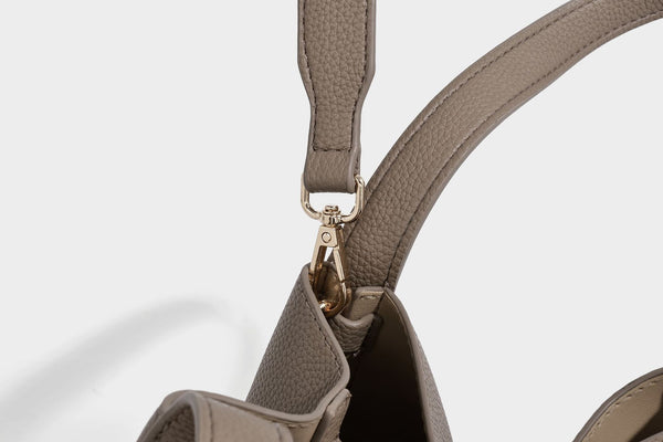 Structured trapezoid tote bag in taupe pebbled leather-look finish with gold-tone turn-lock hardware, dual top handles, and