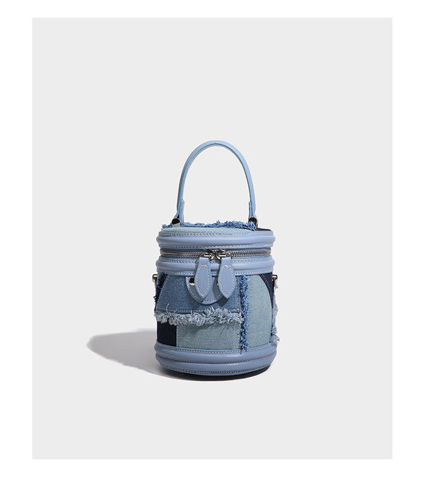 Mini cylindrical barrel bucket bag in denim patchwork with frayed edges, smooth leather-look trim, zip-around top closure