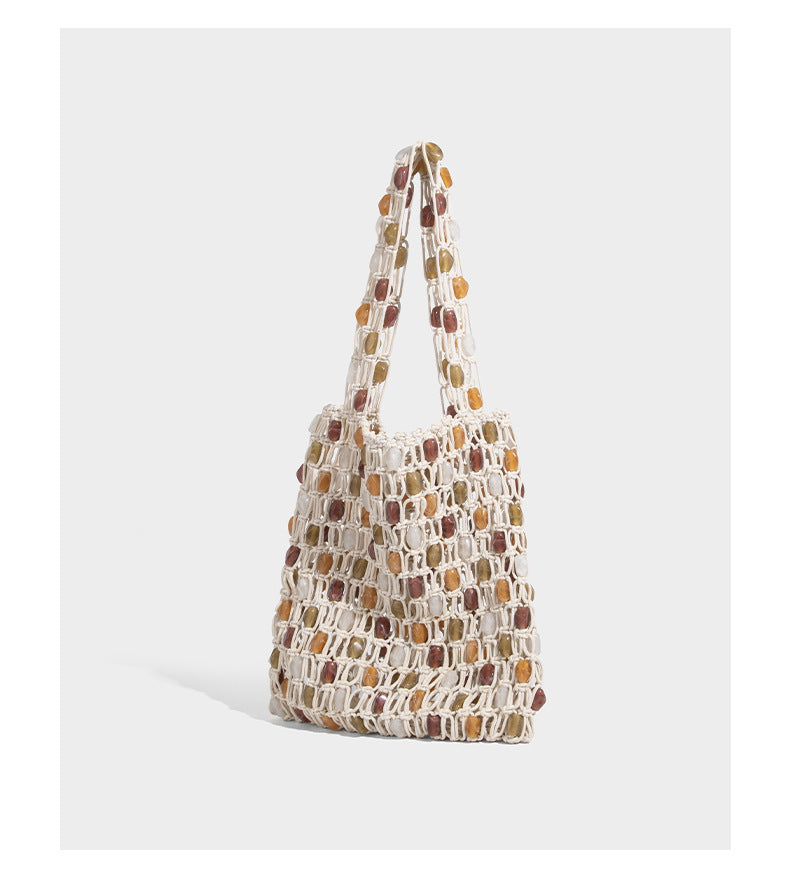 Cream macramé open-weave tote bag with multicolor amber olive and translucent bead accents and woven shoulder straps, detail